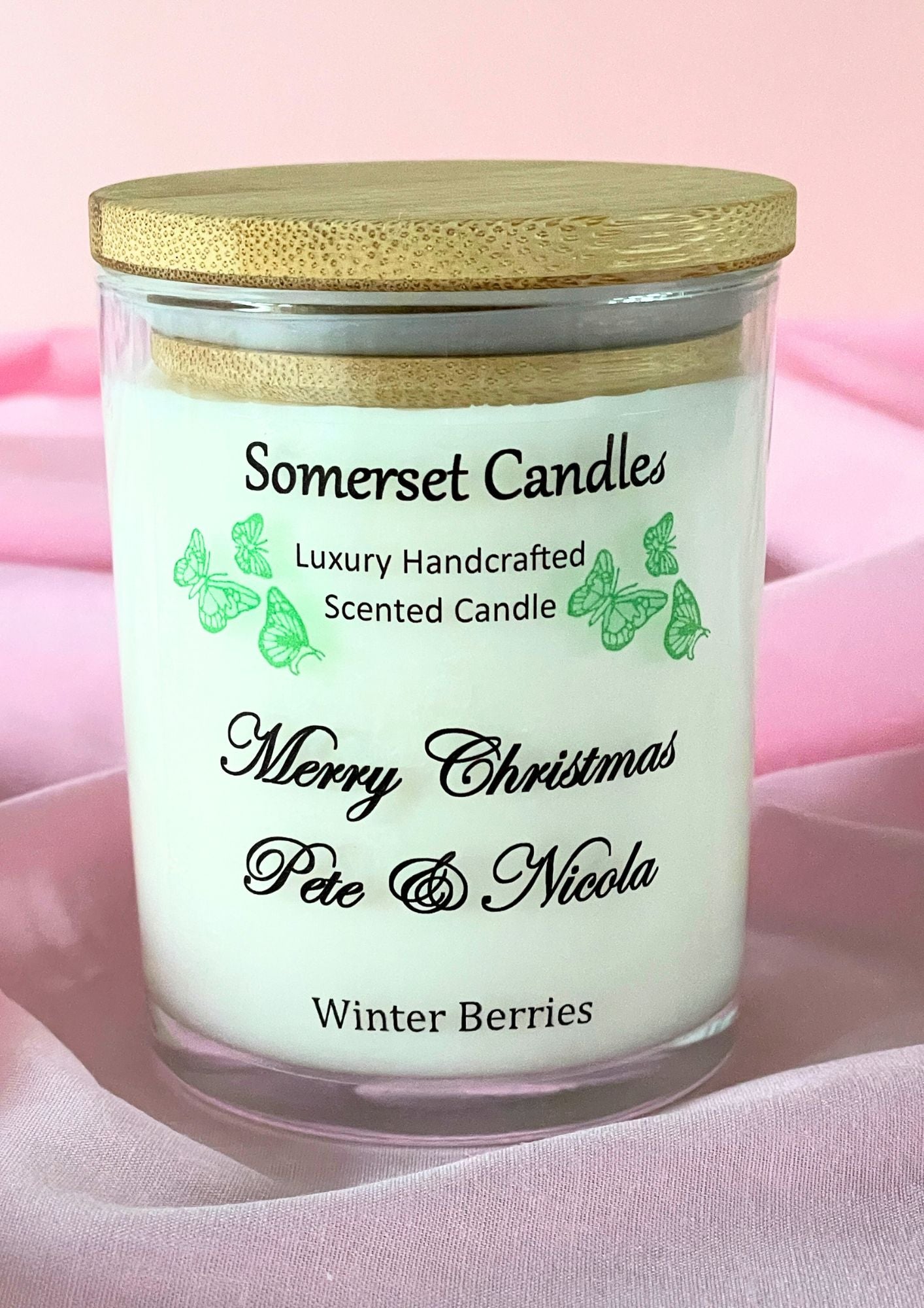 Somerset Candles scented candle with personalized text on a pink fabric background