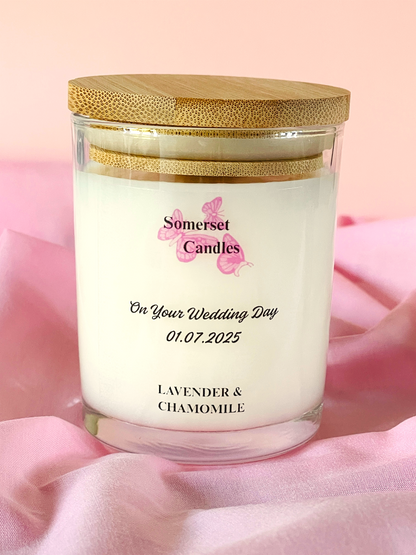 Personalized candle with wooden lid on a pink fabric background, featuring 'Somerset Candles' branding.