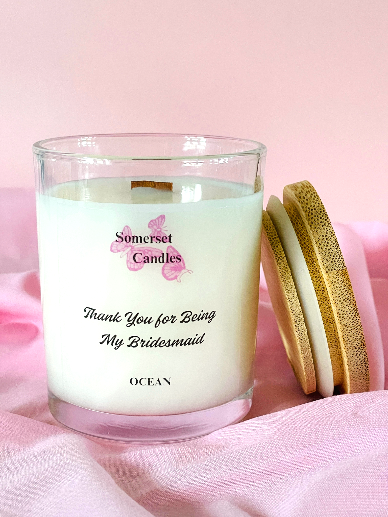 Scented Candle with 'Somerset Candles' branding and text on a pink fabric background