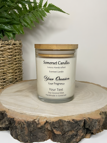 Personalised Scented Soy Candle displayed on a wooden log with a plant behind. The candle is white in colour with no butterflies above the scent name and a lovely bamboo lid.