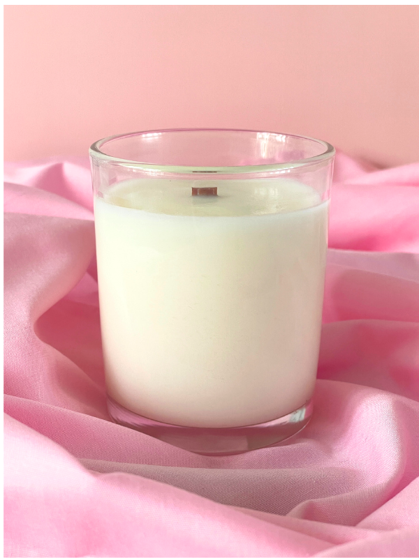 Glass candle on pink fabric with a soft pink background