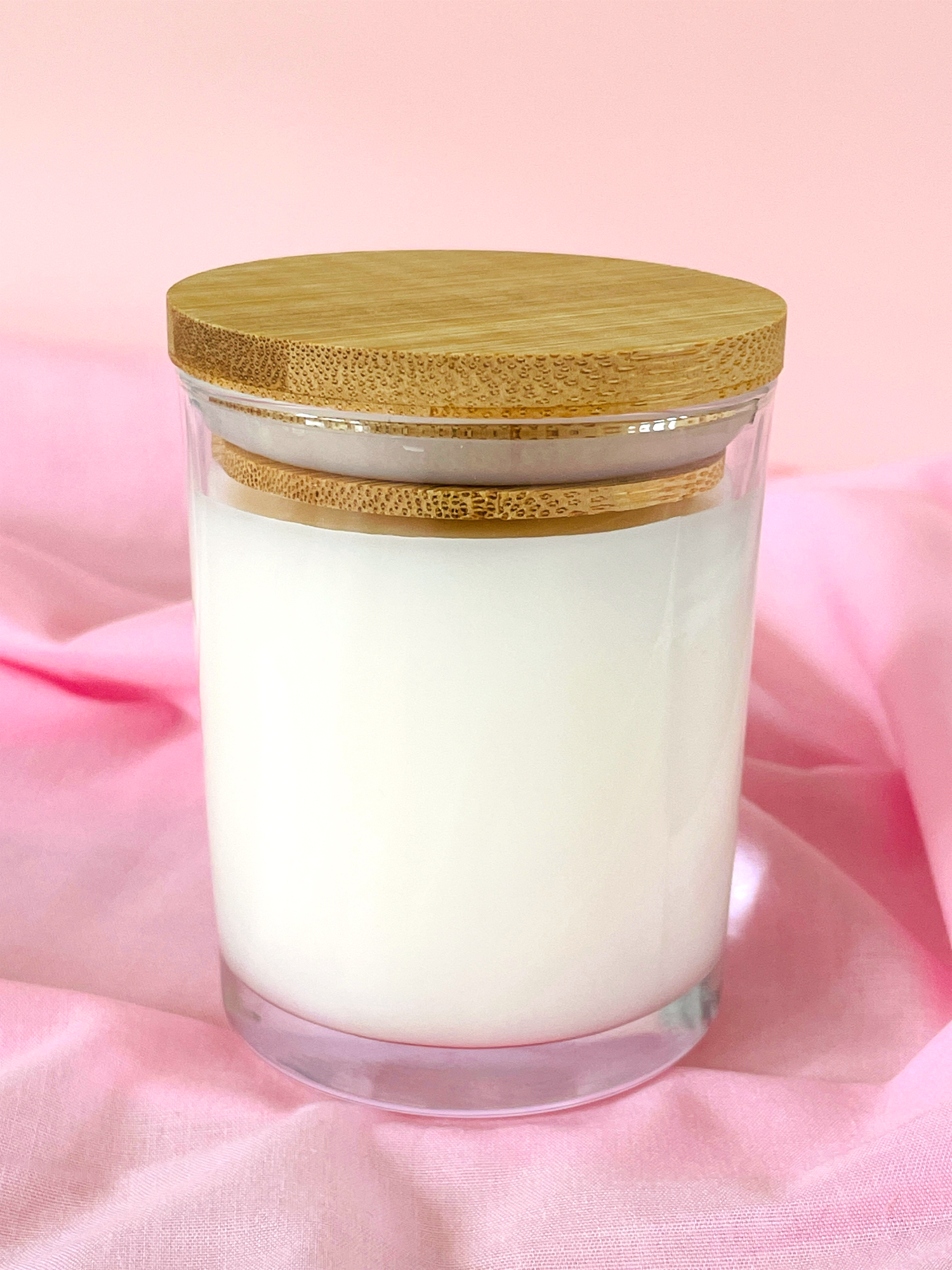7oz glass candle jar with a wooden lid on a pink fabric background