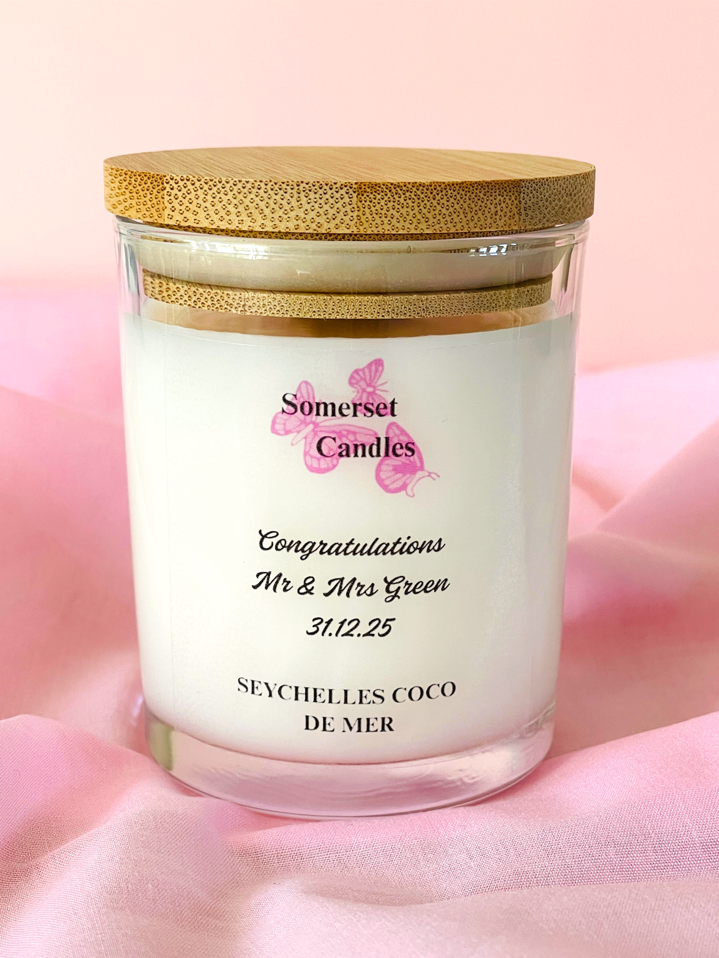 Personalised candle with wooden lid on a pink background, featuring 'Somerset Candles' branding.