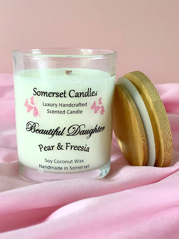 Somerset Candles 'Beautiful Daughter' pear & freesia candle on a pink fabric background