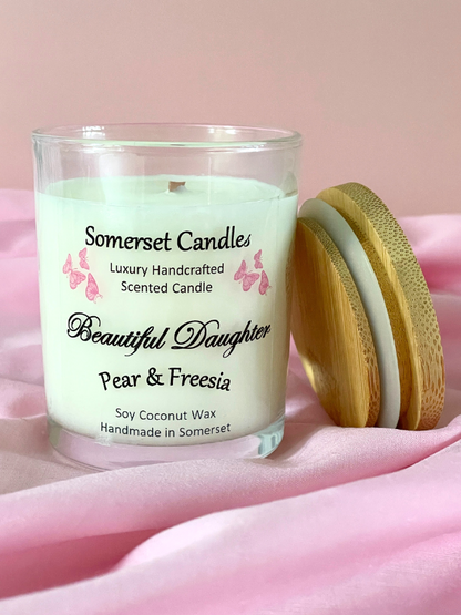 Somerset Candles 'Beautiful Daughter' pear & freesia candle on a pink fabric background