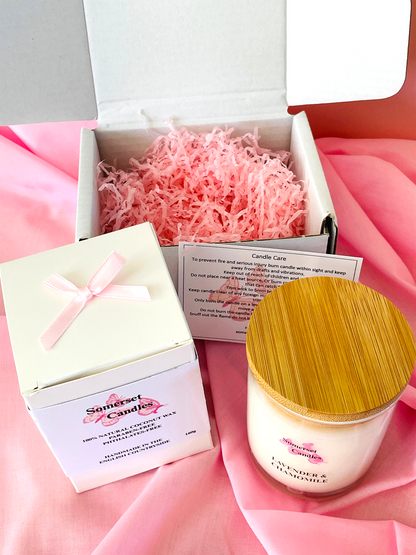 Candle with wooden lid and packaging on a pink fabric background