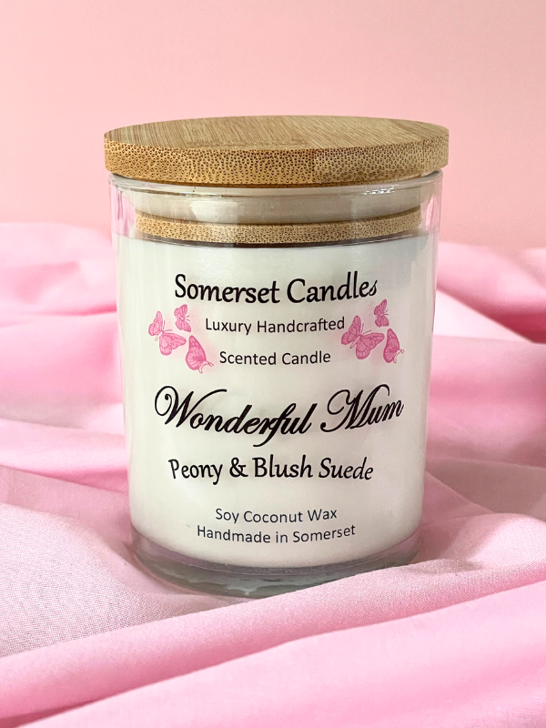 Somerset Candles scented candle with wooden lid on a pink fabric background