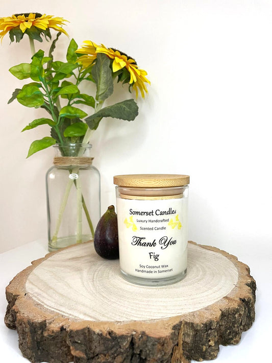 White soy candle in a 7oz clear glass jar with a natural wooden lid. The candle is made from a soy-coconut blend and scented with ripe fig. Above the scent name on the label, several yellow butterflies are displayed, adding a romantic touch. Clean, minimalist design ideal for gifts, home decor or self-care.