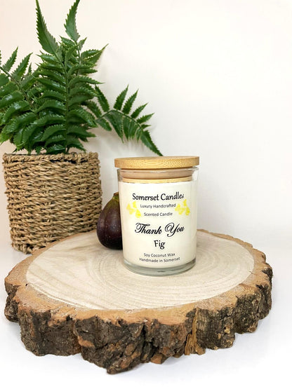 White soy candle in a 7oz clear glass jar with a natural wooden lid. The candle is made from a soy-coconut blend and scented with ripe fig. Above the scent name on the label, several yellow butterflies are displayed, adding a romantic touch. Clean, minimalist design ideal for gifts, home decor or self-care.