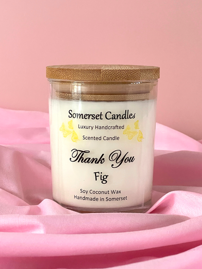 Somerset Candles scented candle with a wooden lid on a pink fabric background