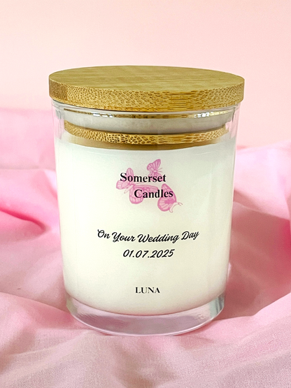 Somerset Candles wedding-themed candle with a wooden lid on a pink fabric background