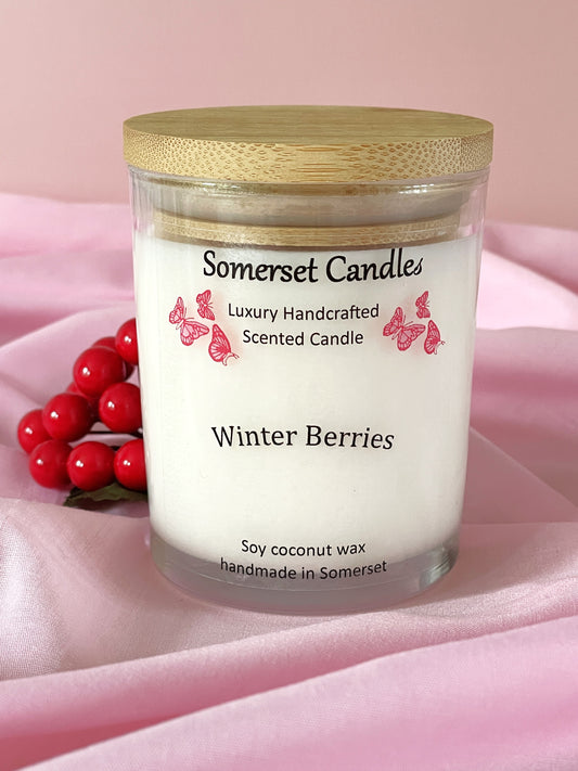 Somerset Candles Winter Berries candle with a wooden lid on a pink background