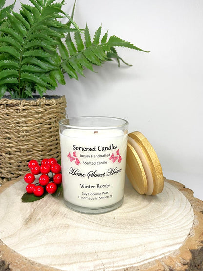White soy candle in a 7oz clear glass jar with a natural wooden lid. The candle is made from a soy-coconut blend and scented with fruity winter berries. Above the scent name on the label, several red butterflies are displayed, adding a romantic touch. Clean, minimalist design ideal for gifts, home decor or self-care.