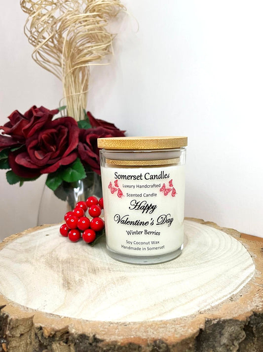 White soy candle in a 7oz clear glass jar with a natural wooden lid. The candle is made from a soy-coconut blend and scented with fruity winter berries. Above the scent name on the label, several red butterflies are displayed, adding a romantic touch. Clean, minimalist design ideal for gifts, home decor or self-care.