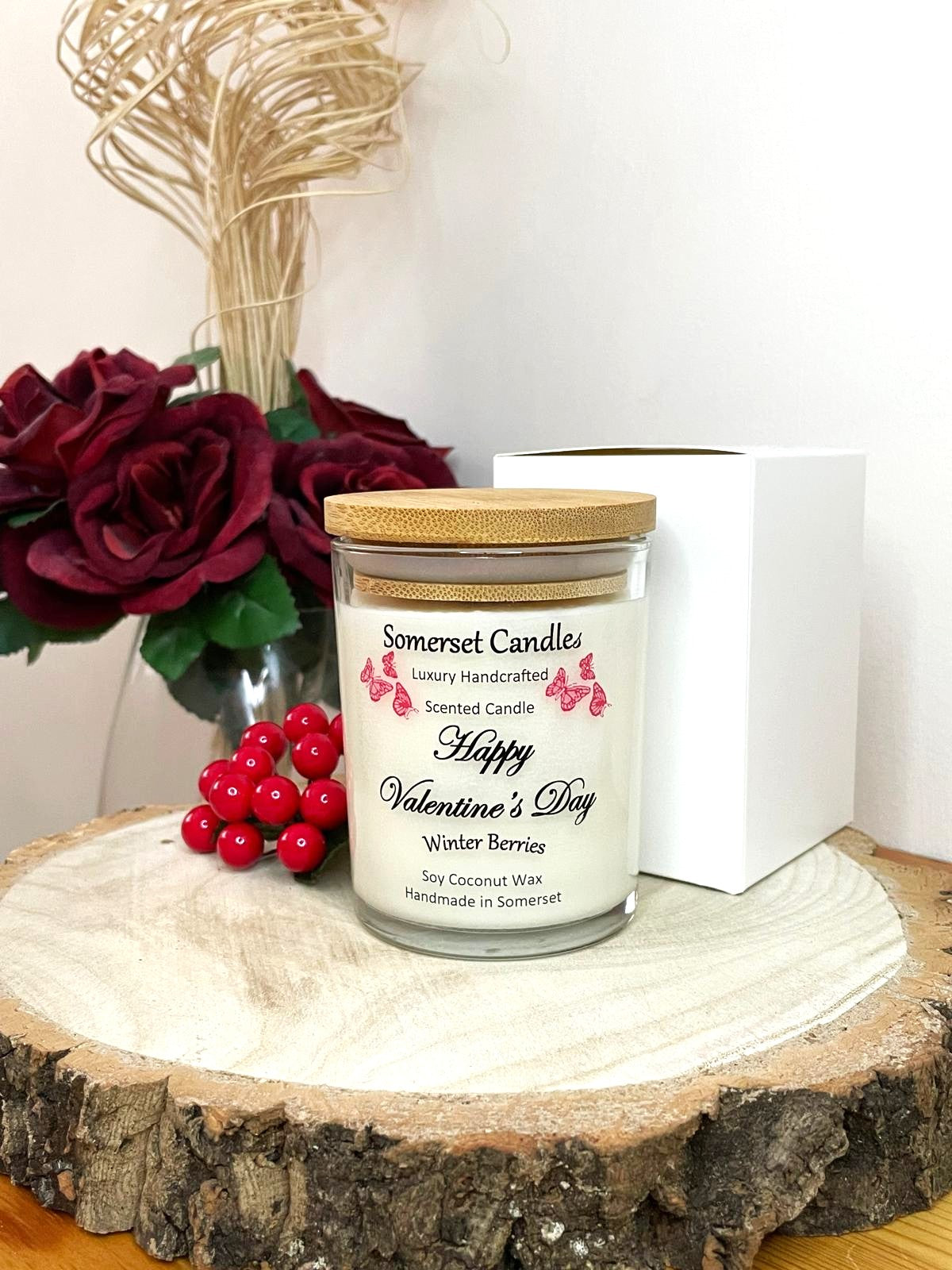 White soy candle in a 7oz clear glass jar with a natural wooden lid. The candle is made from a soy-coconut blend and scented with fruity winter berries. Above the scent name on the label, several red butterflies are displayed, adding a romantic touch. Clean, minimalist design ideal for gifts, home decor or self-care.