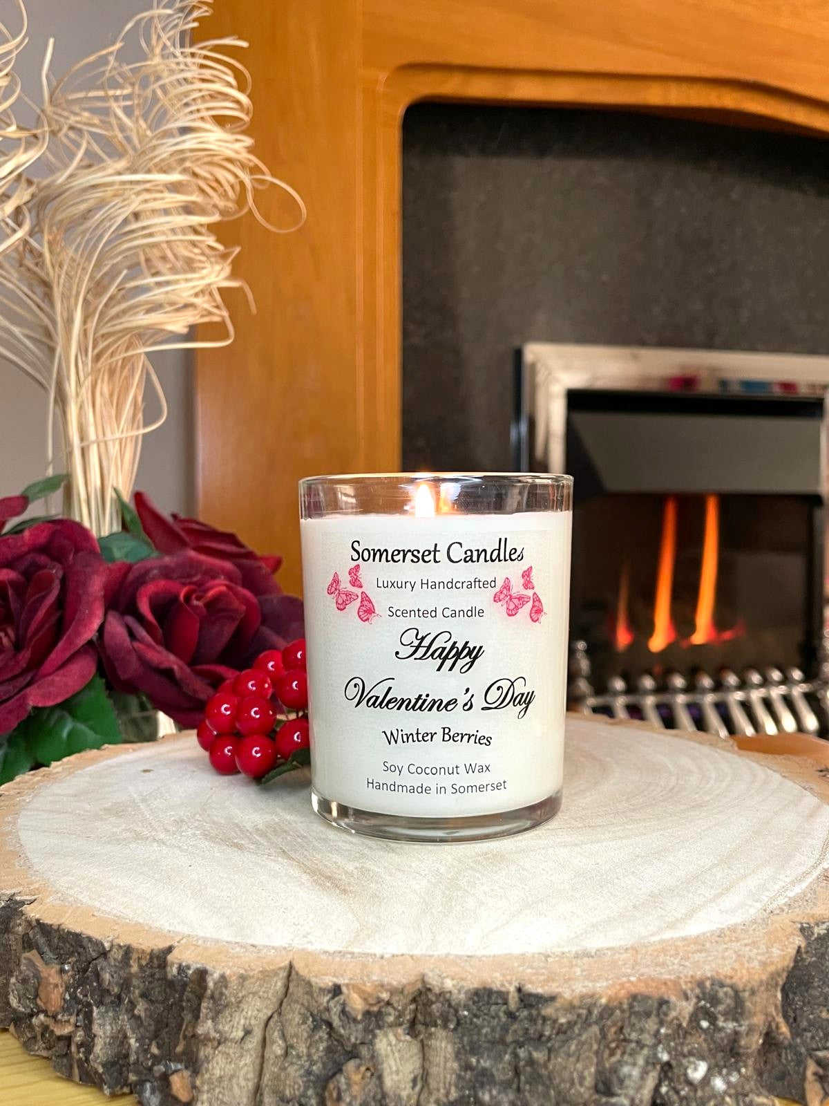 White soy candle in a 7oz clear glass jar with a natural wooden lid. The candle is made from a soy-coconut blend and scented with fruity winter berries. Above the scent name on the label, several red butterflies are displayed, adding a romantic touch. Clean, minimalist design ideal for gifts, home decor or self-care.
