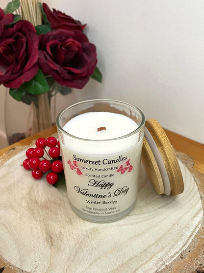 White soy candle in a 7oz clear glass jar with a natural wooden lid. The candle is made from a soy-coconut blend and scented with fruity winter berries. Above the scent name on the label, several red butterflies are displayed, adding a romantic touch. Clean, minimalist design ideal for gifts, home decor or self-care.